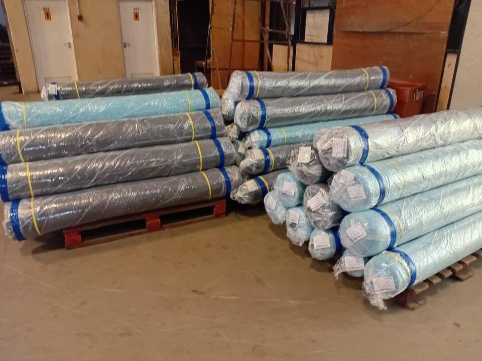 Wrapped rolls of material stacked on wooden pallets