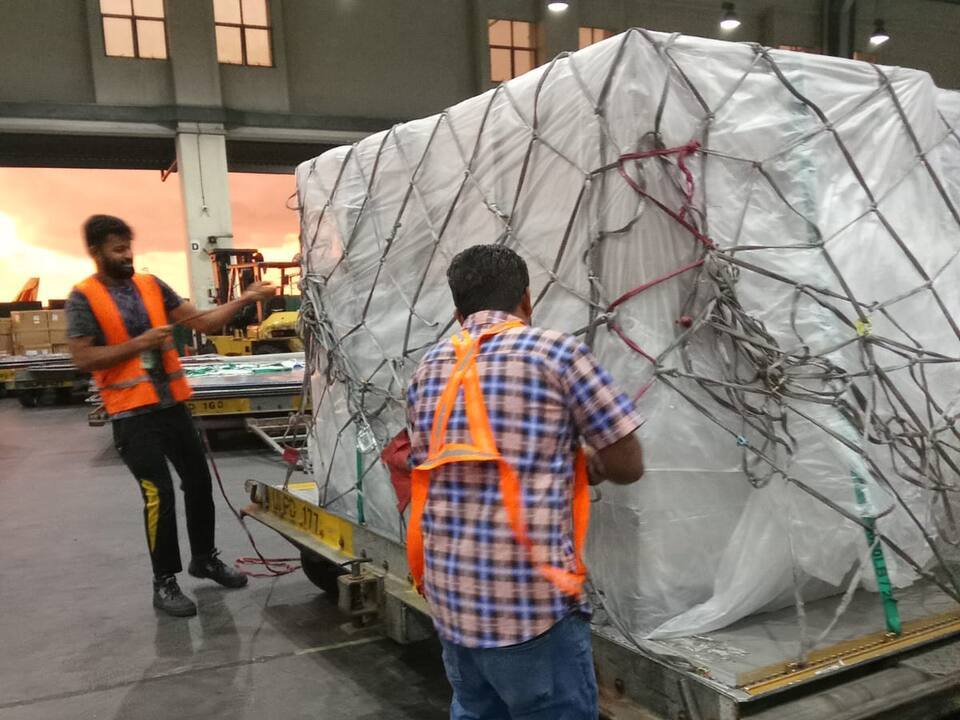 Workers tightening the cargo net over a wrapped pallet